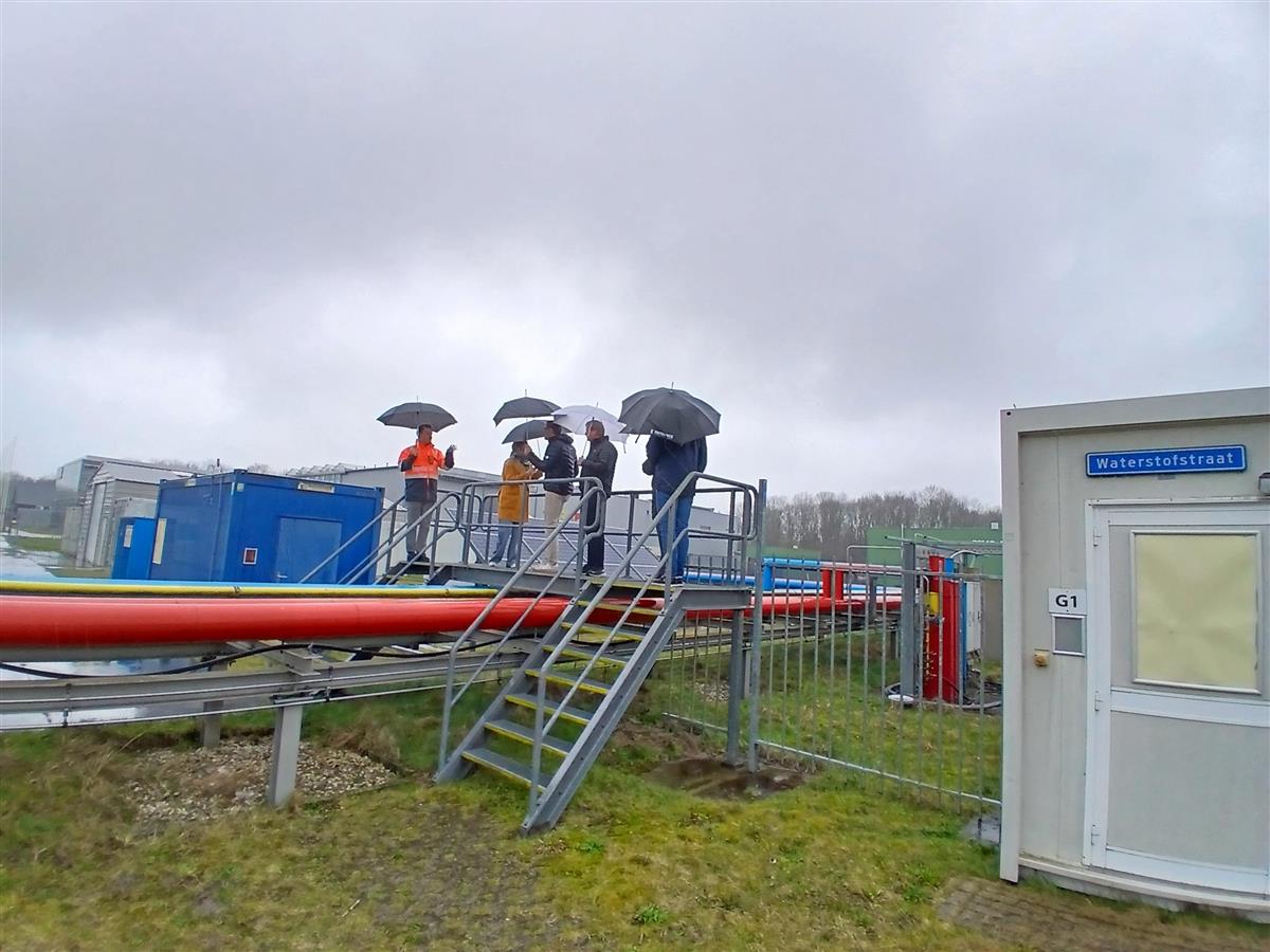 personer med paraplye står på en bro over noen fargede rød - Klikk for stort bilde