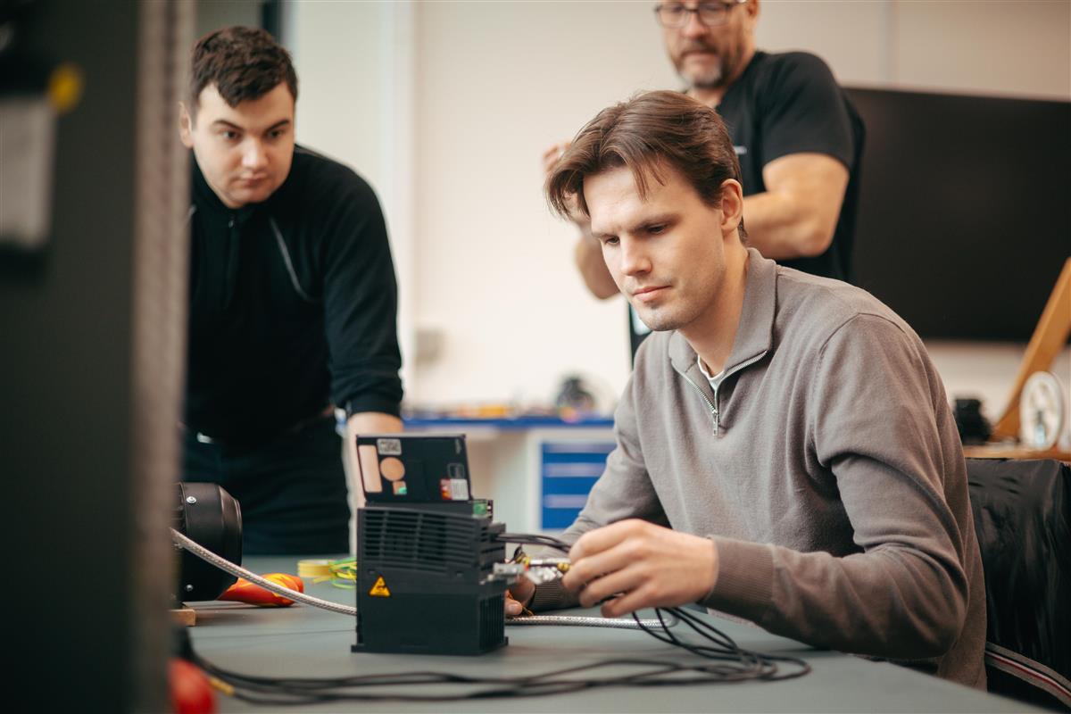 to studenter jobber med en teknisk oppgave, mens en lærer ser på - Klikk for stort bilde