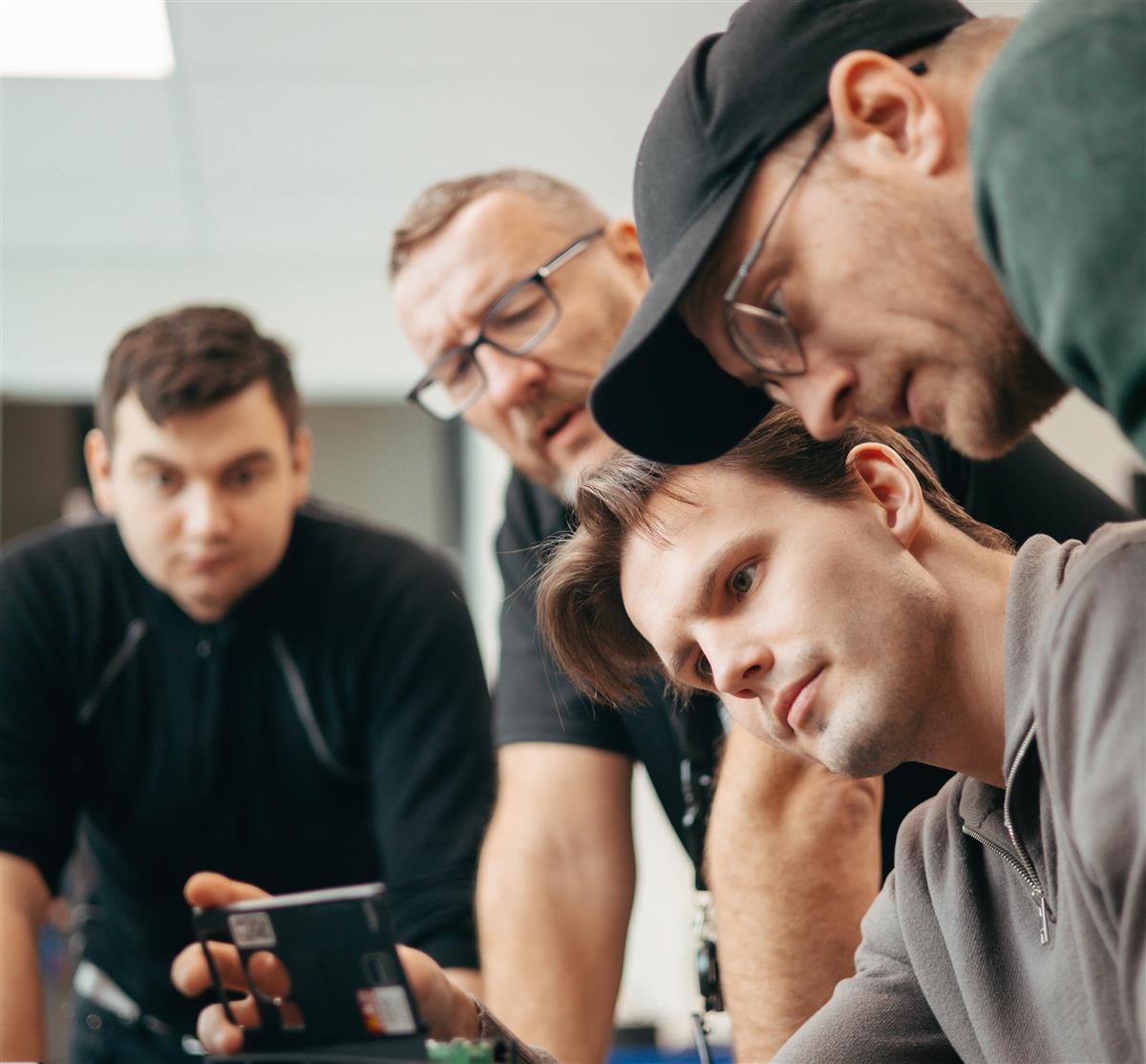 3 studenter og en lærer ser på et teknisk element - Klikk for stort bilde