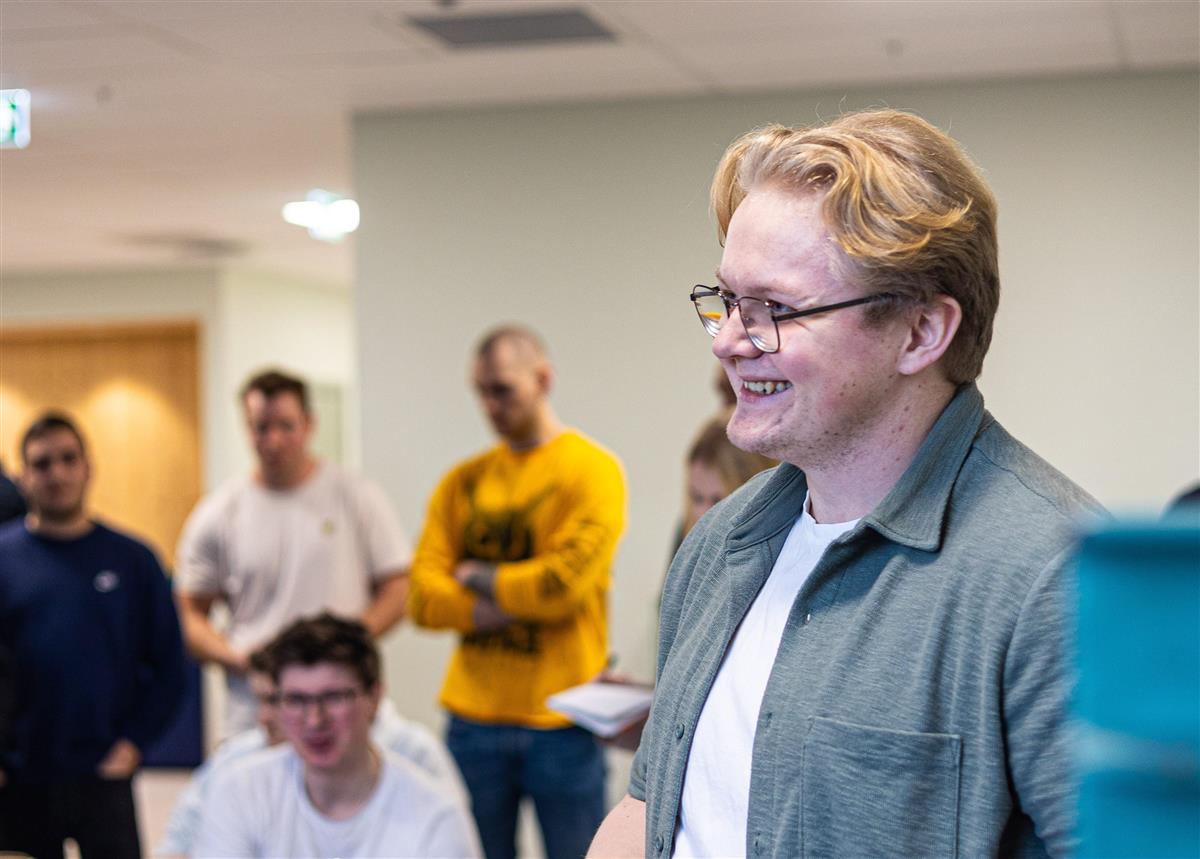 Bilde av en ung mann som står foran en gruppe - Klikk for stort bilde